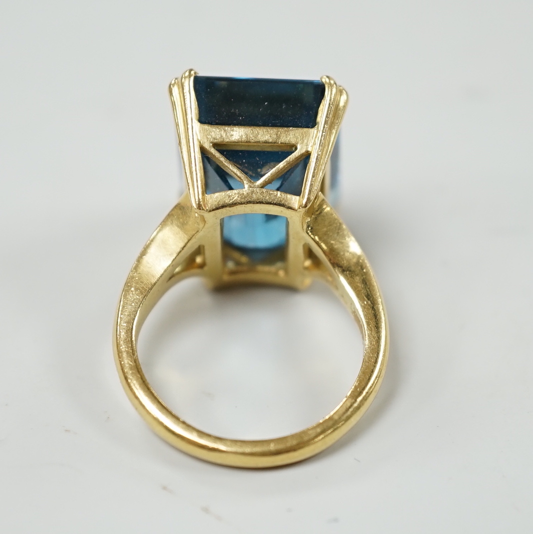 An 18ct and emerald cut blue topaz set dress ring, size K, gross weight 11 grams.